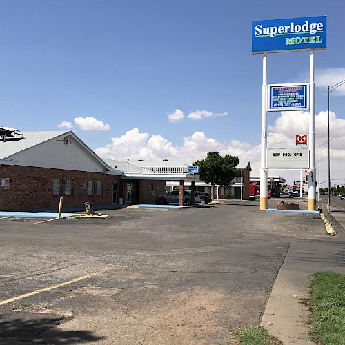 An image of a Superlodge Motel with an empty parking lot, a large sign, and a clear sky in the background ends the sentence.