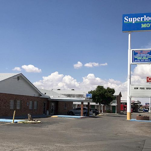 The image shows a roadside motel named Superlodge with a large, prominent sign, parking area, and connected buildings under a blue sky.